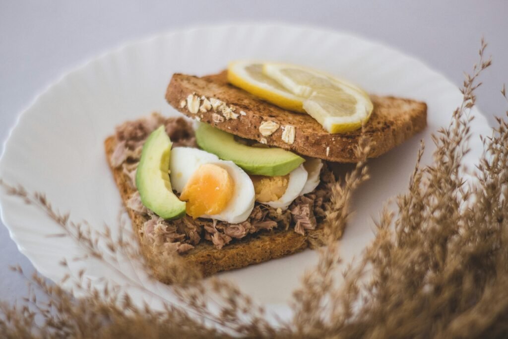 Home Delicious homemade tuna sandwich with avocado slices and boiled egg on wheat bread.